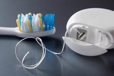 soft bristled tooth brush next to floss