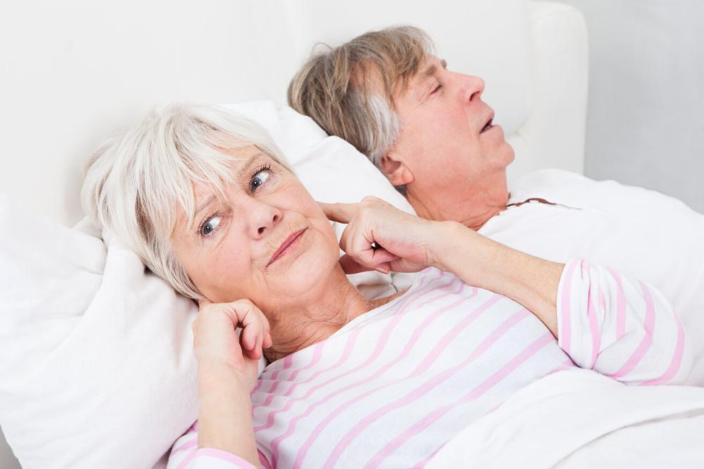 woman covering ears from husband snoring