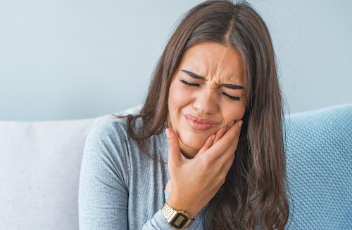 woman holding jaw pain from infected tooth