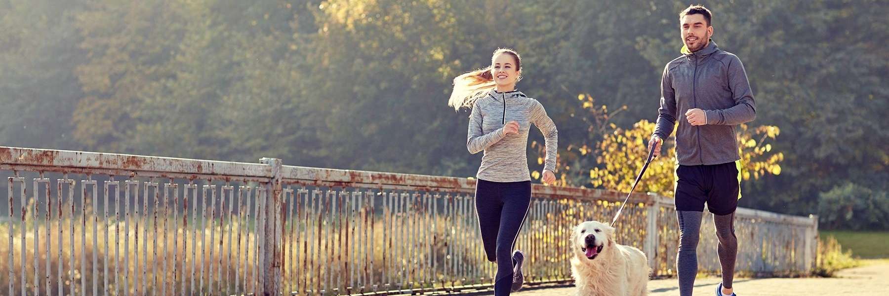 Couple running with their dog at Holmes Lake Park in Lincoln, NE 