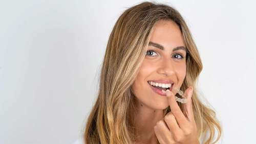 smiling woman putting on her clear aligner braces