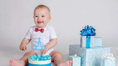 toddler sitting with birthday cake and presents