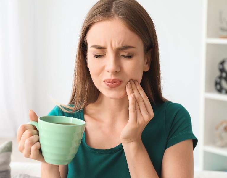 woman holding jaw from tooth pain during dental emergency in lincoln 