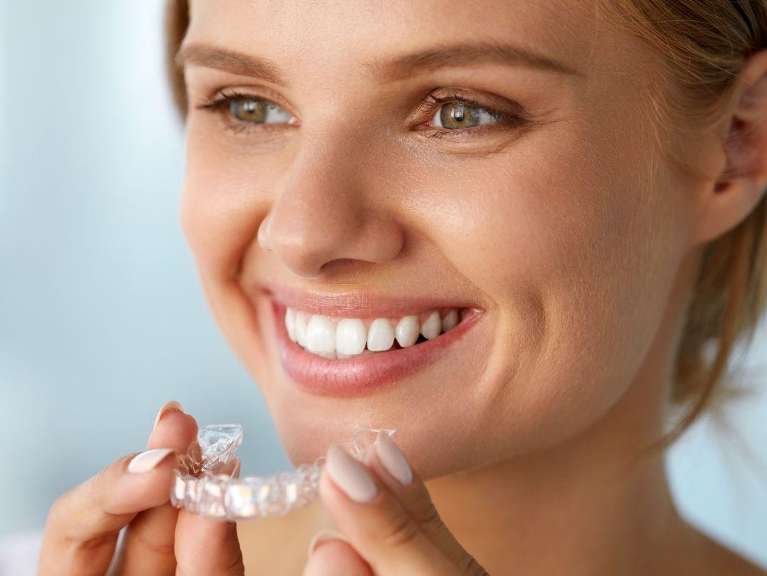 woman smiling while holding clearcorrect aligners