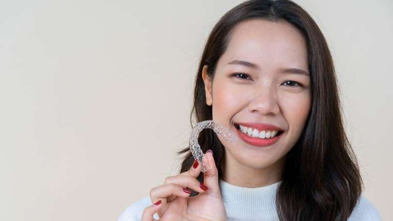 woman holding clear aligners 