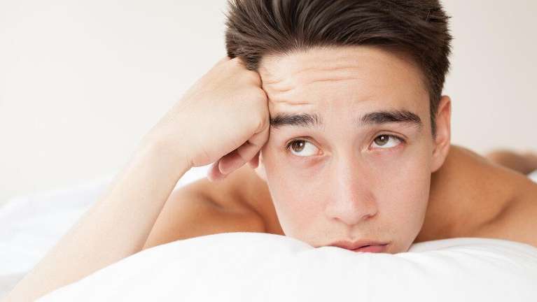 man looking frustrated while resting on pillow
