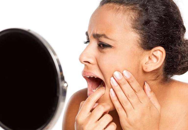 woman checking tooth in mirror during a dental emergency