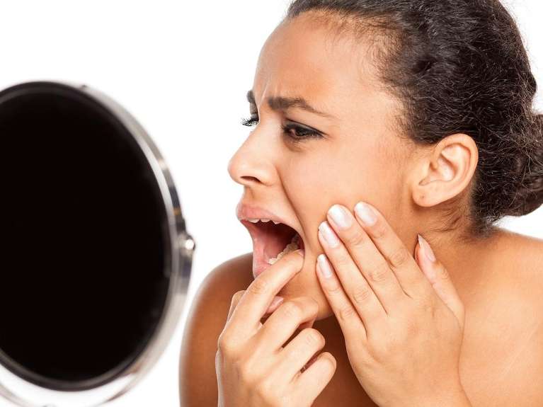 Woman checking her tongue and mouth in the mirror for oral health problems at Antelope Creek Family 