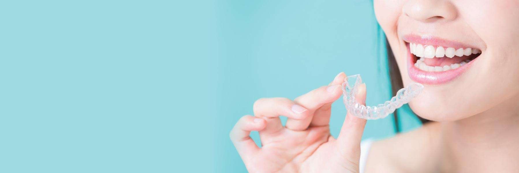close up of woman holding clear aligners 