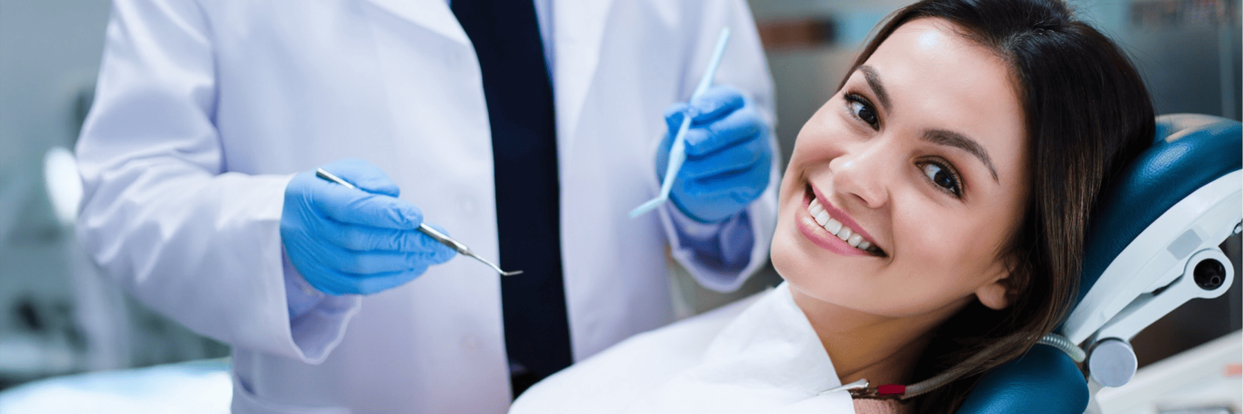 Smiling young woman in dental chair consulting with dentist about cosmetic smile options